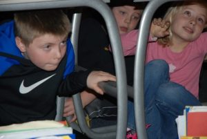 Three children under their desks during an earthquake drill.