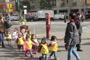 Ten toddlers and two teachers practicing an evacuation drill by holding onto a rope and leaving the building